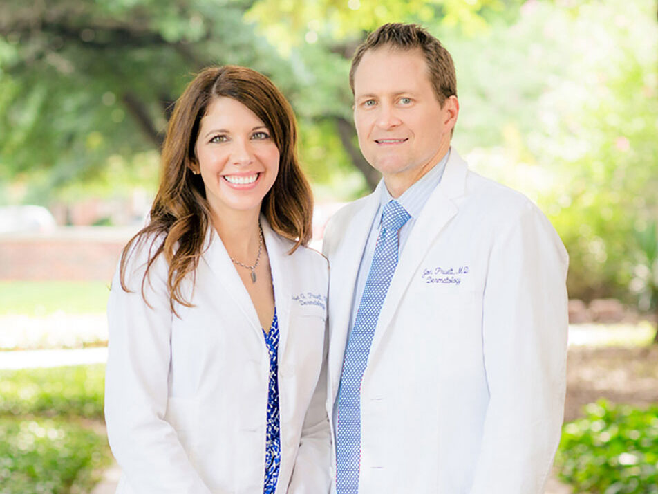Portrait of smiling female and male doctors standing outside on a sunny day.